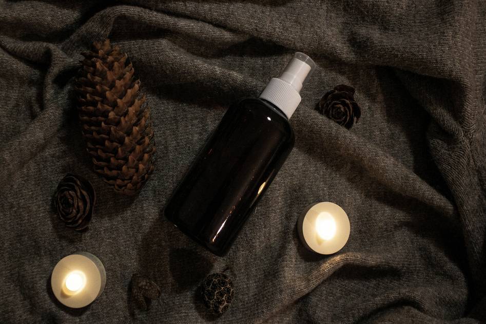 Witch hazel toner bottle with fresh green leaves on soft beige surface